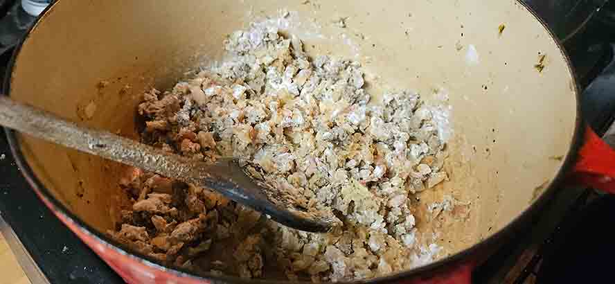 Cooking flour with bacon fat and onions to create a smooth, bubbling blond roux in a Dutch oven.