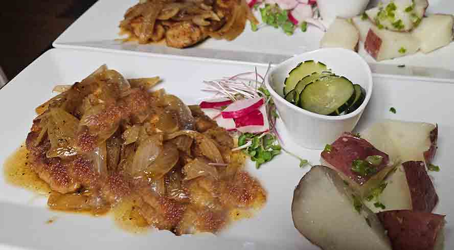 A traditional German dinner of breaded Schnitzel with onion gravy, served with buttered boiled potatoes and a creamy cucumber salad
