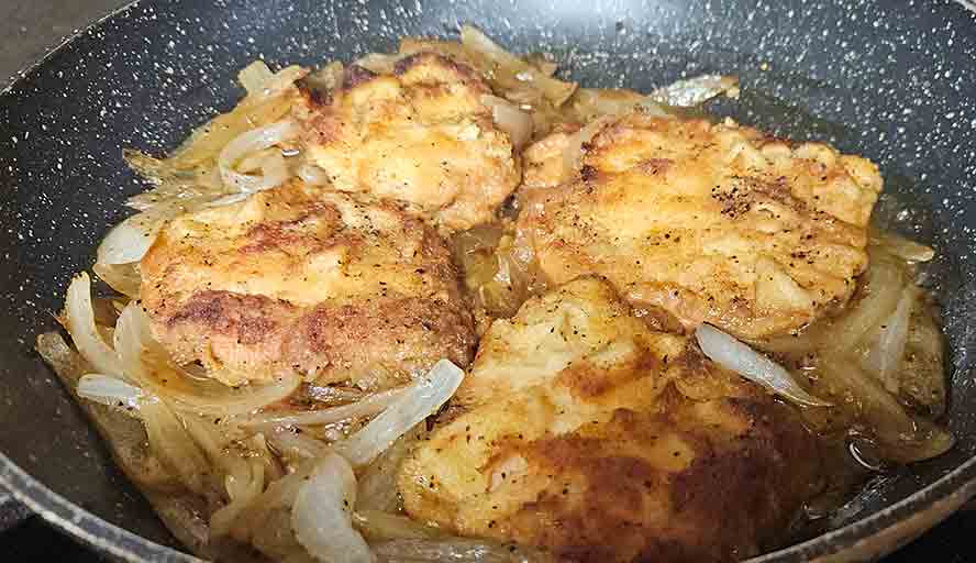 "Breaded Schnitzel smothered in a thick, glossy onion gravy reduced from savory stock."