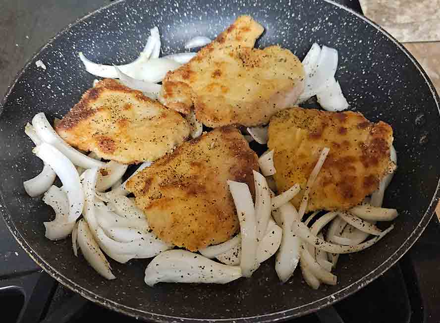 Turn the Schnitzels and put the raw onion slices underneath. 