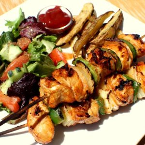Chicken Schaschlik skewered on a plate with salad.