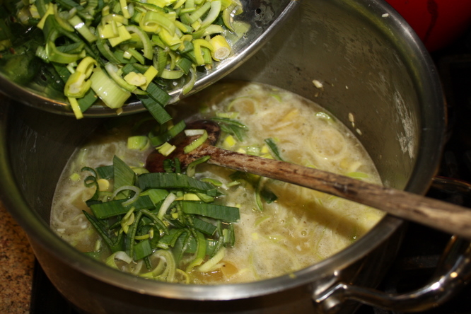 Adding more leeks to simmering soup
