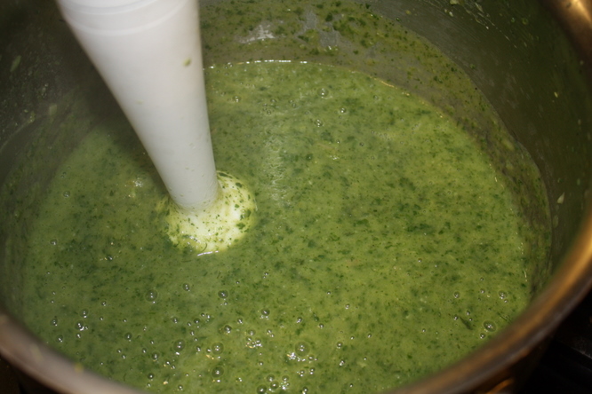 Blending spring herb soup with immersion blender