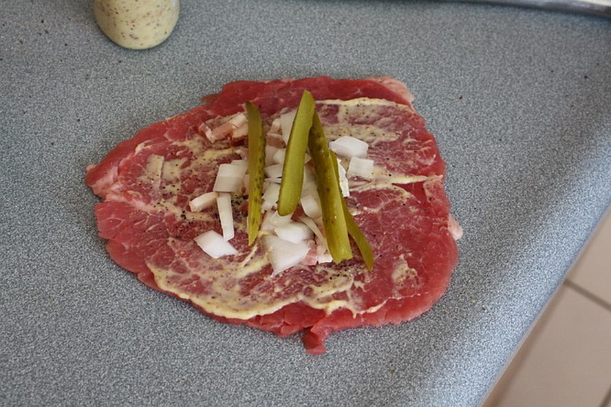 Thin beef steak spread with mustard and topped with onions and pickles for rouladen