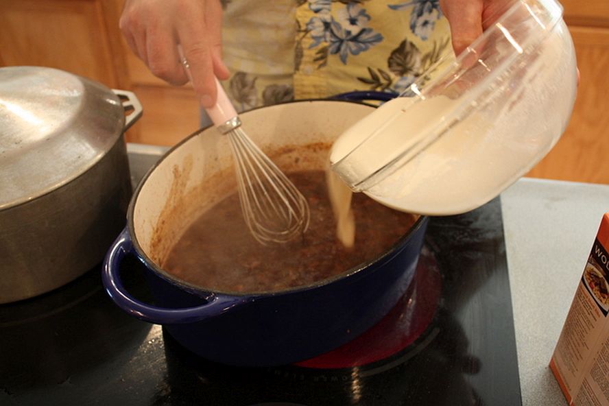 Whisking slurry into gravy to thicken rouladen sauce