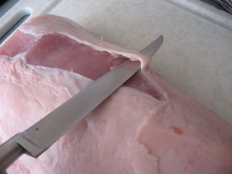 knife trimming fat and silver skin from pork loin