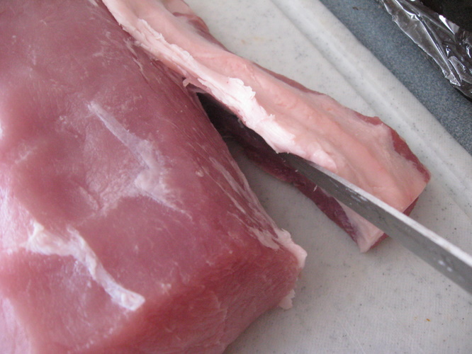 removing excess fat from pork loin with a knife