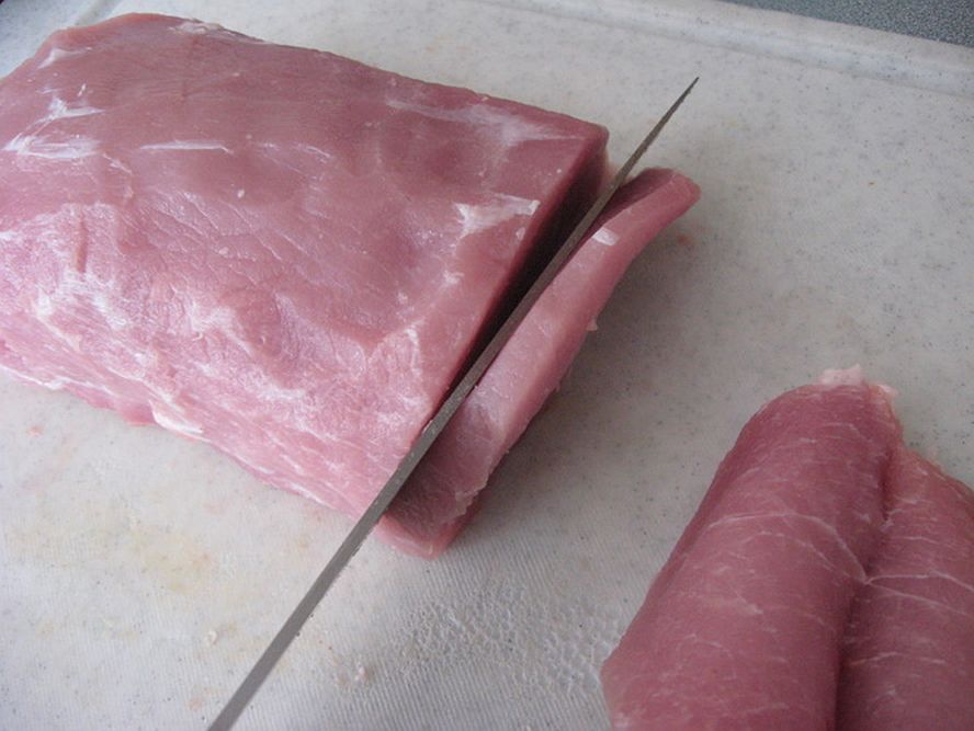slicing pork loin into thick cutlets for schnitzel