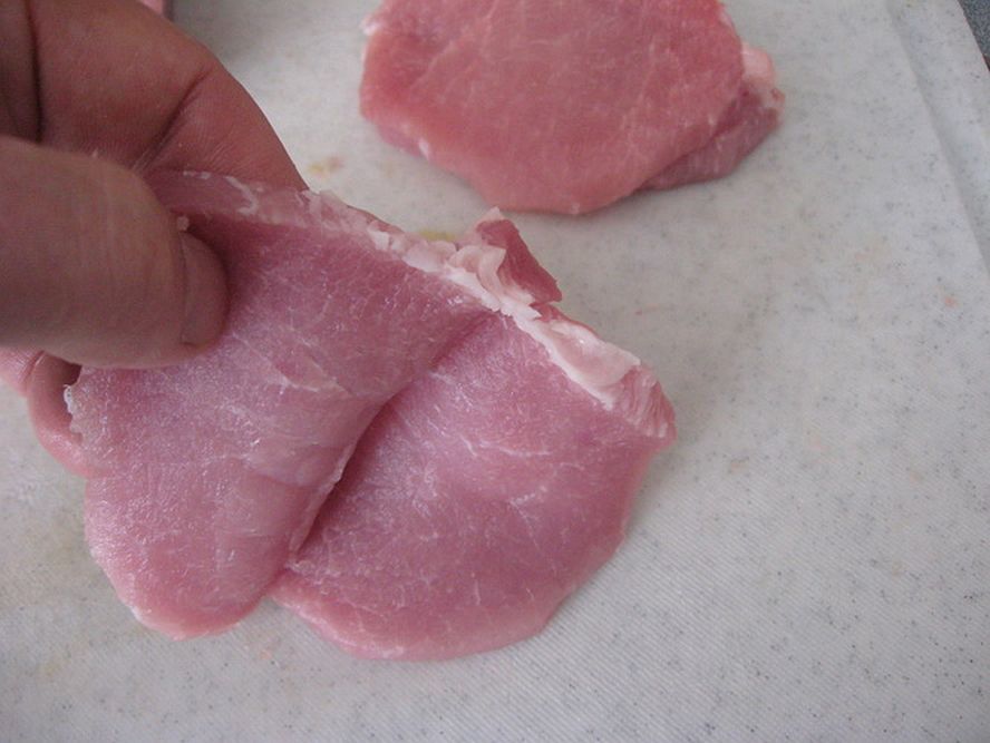 hand holding pork cutlet showing thickness before tenderizing