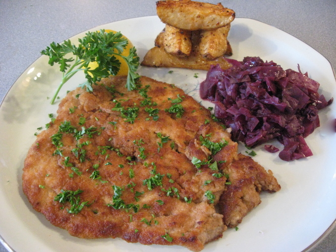 Plated Wienerschnitzel with lemon, and red cabbage.