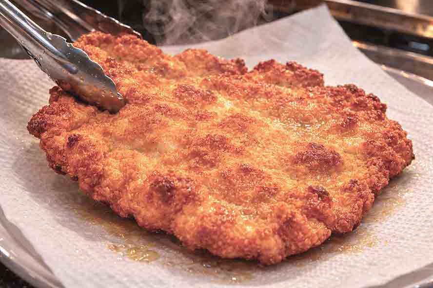 A cooked perfect Schnitzel draining on a paper towel.