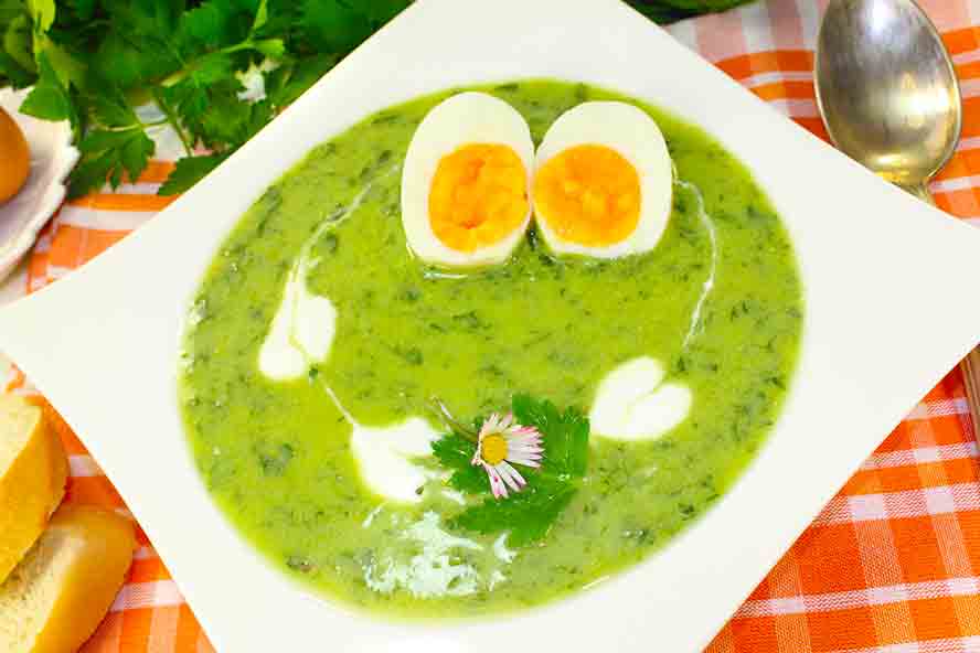 Spring herb soup with soft boiled eggs and cream garnish