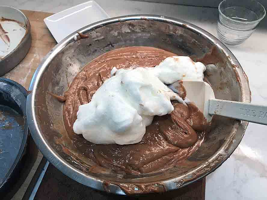 Whipped egg whites being folded into the chocolate cake batter.