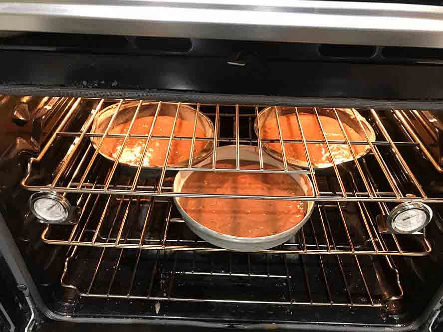 Three pans of chocolate cake baking in the oven.