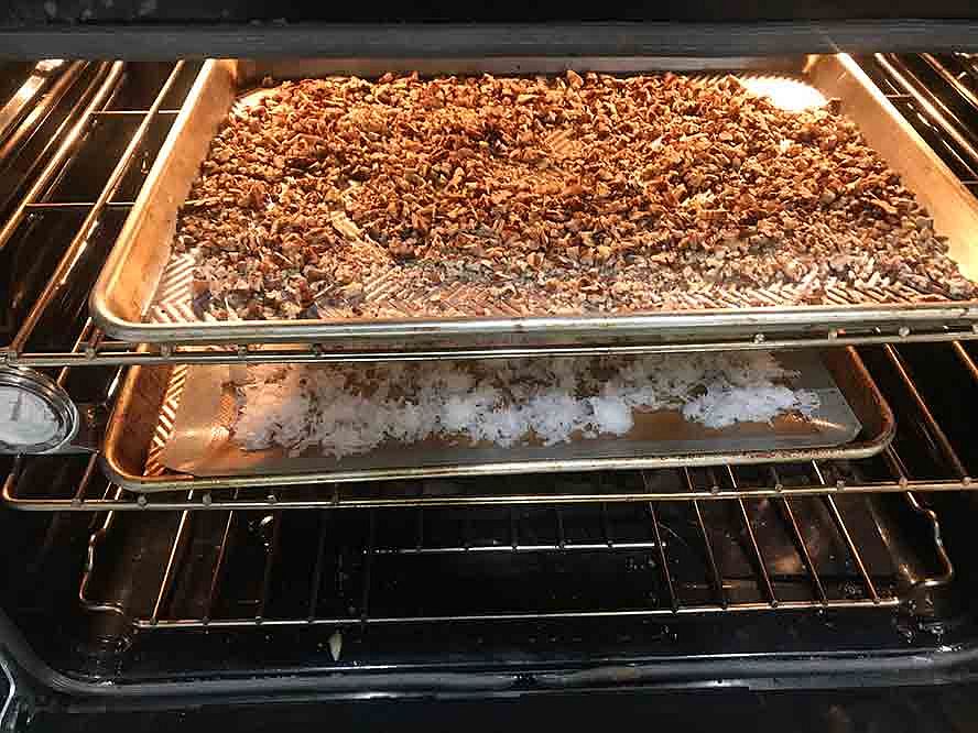 Chopped pecans being toasted in a baking pan in the oven.
