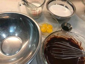 Chocolate mixture, eggs, milk, sugar, and other ingredients prepared for mixing the cake batter.